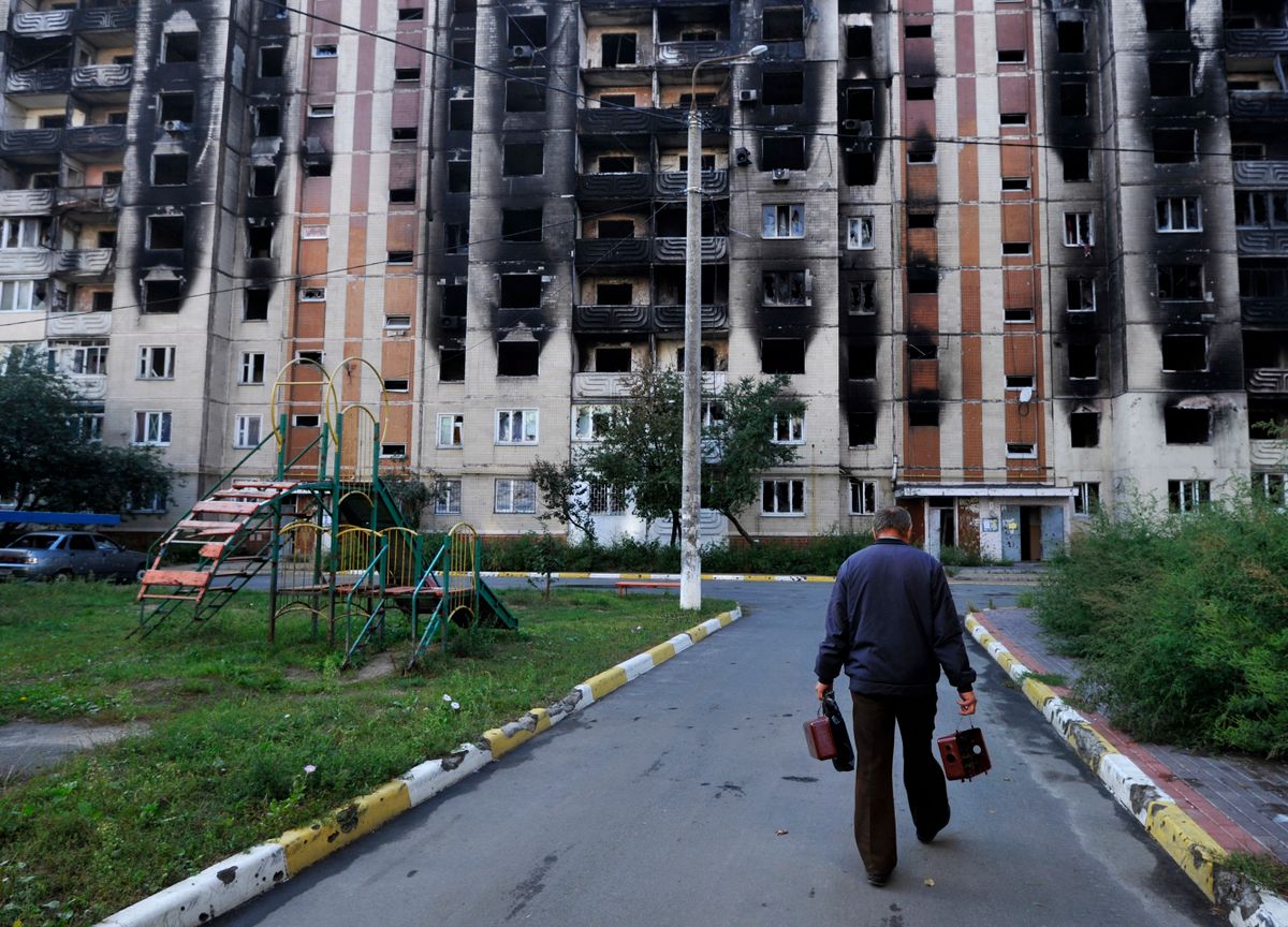 A man walks towards a damaged residential building in the town of Irpin on September 11, 2022, amid the Russian invasion of Ukraine. - Ukraine said on Sptember 11, 2022, that its forces were pushing back Russia's military from strategic holdouts in the east of the country after Moscow announced a retreat from Kyiv's sweeping counter-offensive. (Photo by Sergei CHUZAVKOV / AFP)