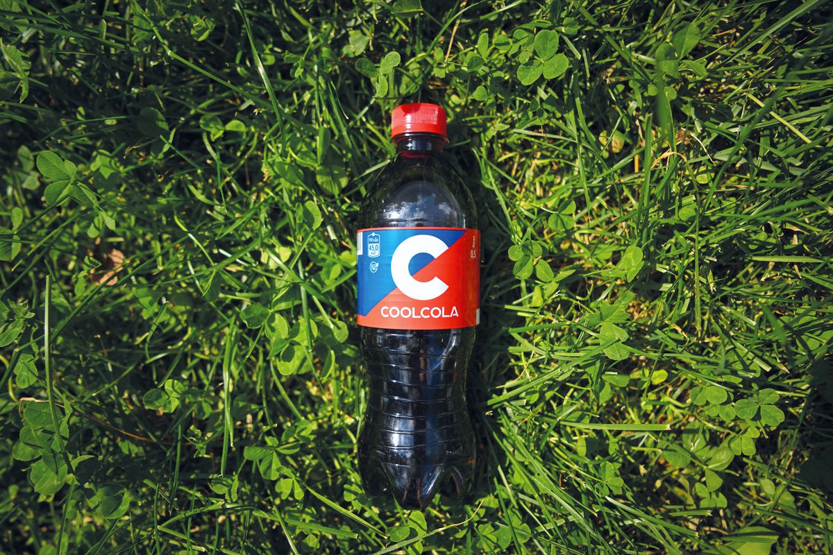 A bottle of soft drink CoolCola, with its name and design resembling Coca-Cola -  the iconic brand of US beverage giant Coca-Cola, is seen on the grass in Moscow on July 25, 2022. - Russian beverage maker Ochakovo launched the production of a new set of soft drinks to replace the three global brands of Coca-Cola after the world's largest soft-drink maker has suspended operations in Russia over the country's military action in Ukraine. (Photo by Natalia KOLESNIKOVA / AFP)