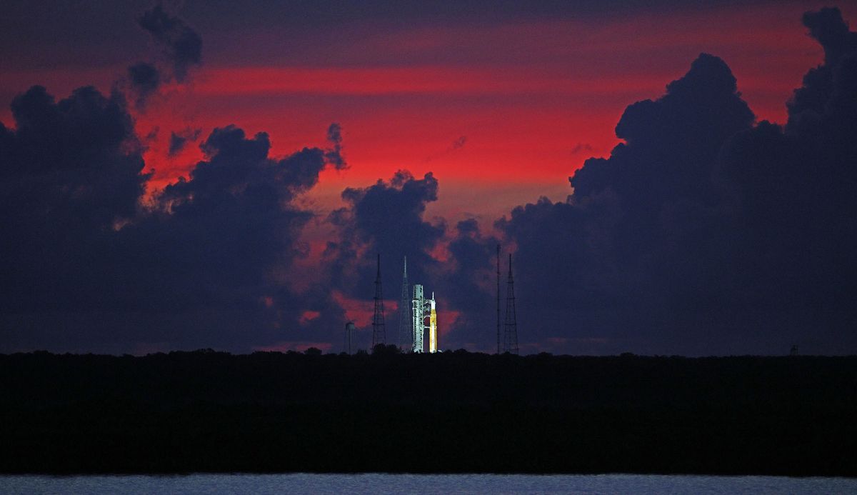The sky begins to clear before dawn, highlighting the Artemis-1 moon rocket at Launch Pad 39 at the Kennedy Space Center, in this view from Titusville, Florida on August 23, 2022. - Artemis 1, an uncrewed test flight, will feature the first blastoff of the massive Space Launch System rocket, which will be the most powerful in the world when it goes into operation. It will propel the Orion crew capsule into orbit around the Moon. The spacecraft will remain in space for 42 days before returning to Earth. (Photo by Gregg Newton / AFP)