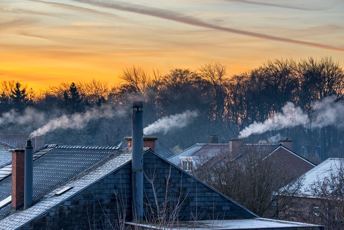 Smoking domestic rooftop chimneys from houses emitting vapour, Smoking domestic rooftop chimneys from houses emitting vapour/vapor from gas boilers for central heating at sunrise on freezing cold winter morning. (Photo by: Philippe Clément/Arterra/Universal Images Group via Getty Images)