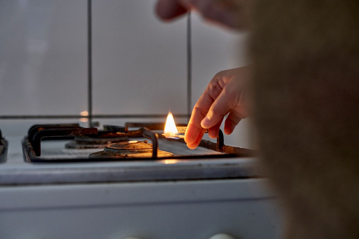 Close-Up Of Hand Lighting Up Gas Stove Burner