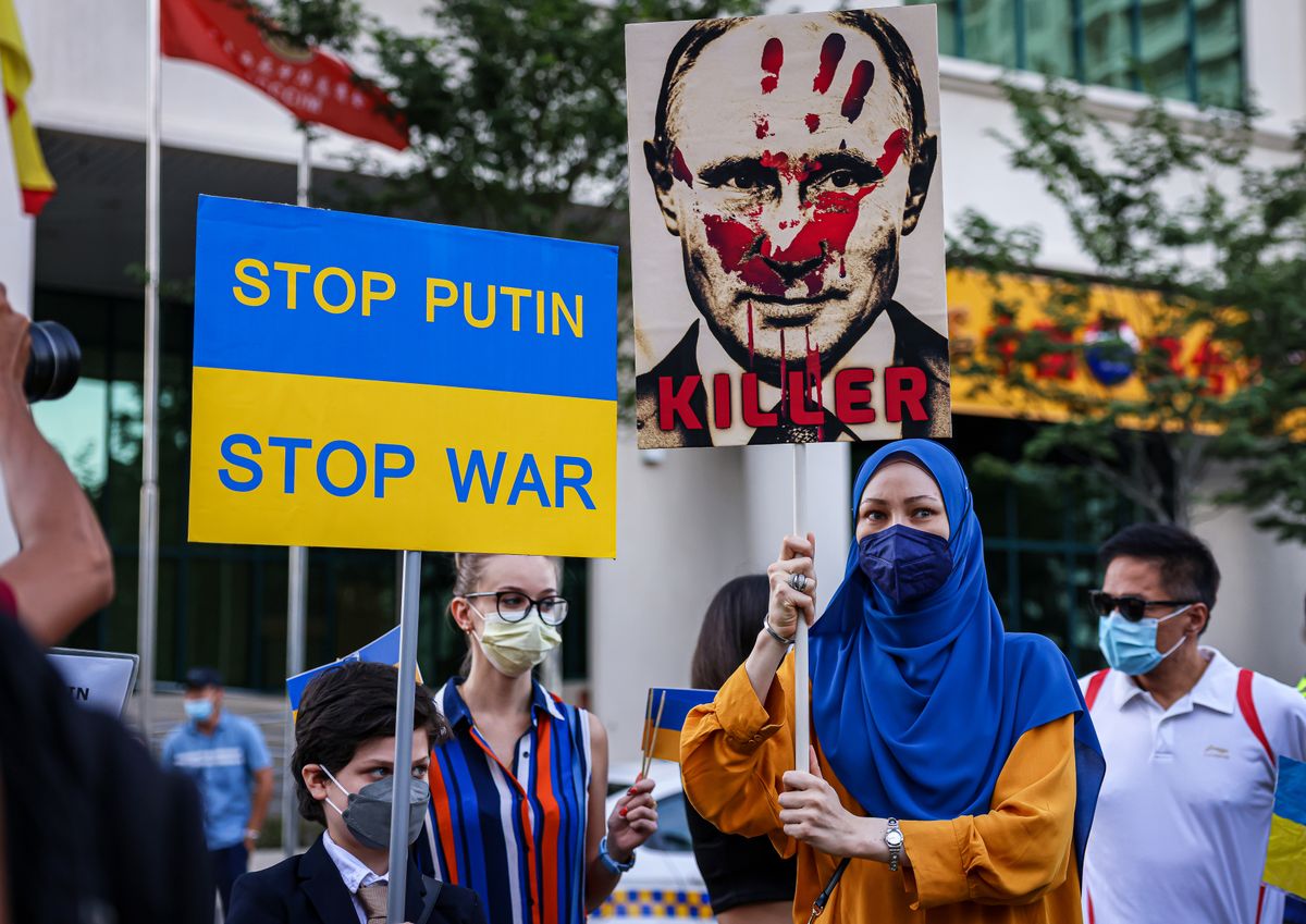 Malaysians Rally In Support Of Ukraine, KUALA LUMPUR, MALAYSIA - FEBRUARY 28: Ukrainian protesters hold up a poster of Russian President Vladimir Putin with the word "killer" and a placard that reads "Stop Putin, Stop War" as they gather during a rally out site the Embassy of Russian Federation on February 28, 2022 in Kuala Lumpur, Malaysia. Protests have erupted around the world in support of Ukraine after Russian forces invaded the country earlier this week. (Photo by Annice Lyn/Getty Images)