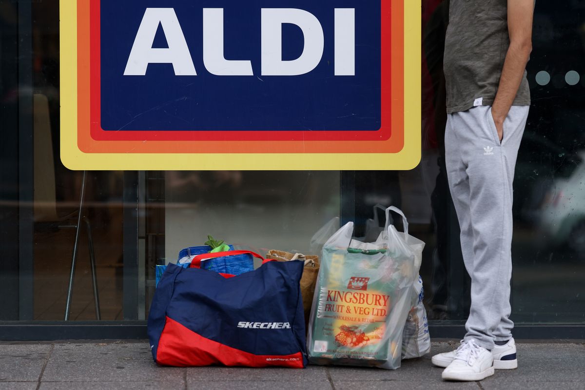 A customer waits outside an Aldi Stores Ltd. supermarket with their groceries in London, UK, on Friday, June 24, 2022. The Office for National Statistics said Friday the volume of goods sold in stores and online fell 0.5% in May, as soaring food prices forced consumers to cut back on spending in supermarkets. 