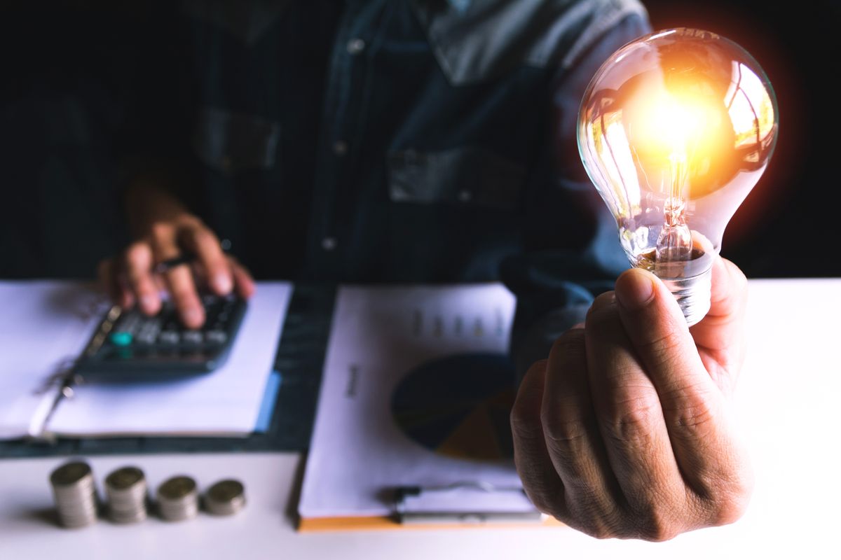 Midsection Of Businessman Holding Illuminated Light Bulb In Office, Hand of male holding a light bulb for innovation and creative concept .