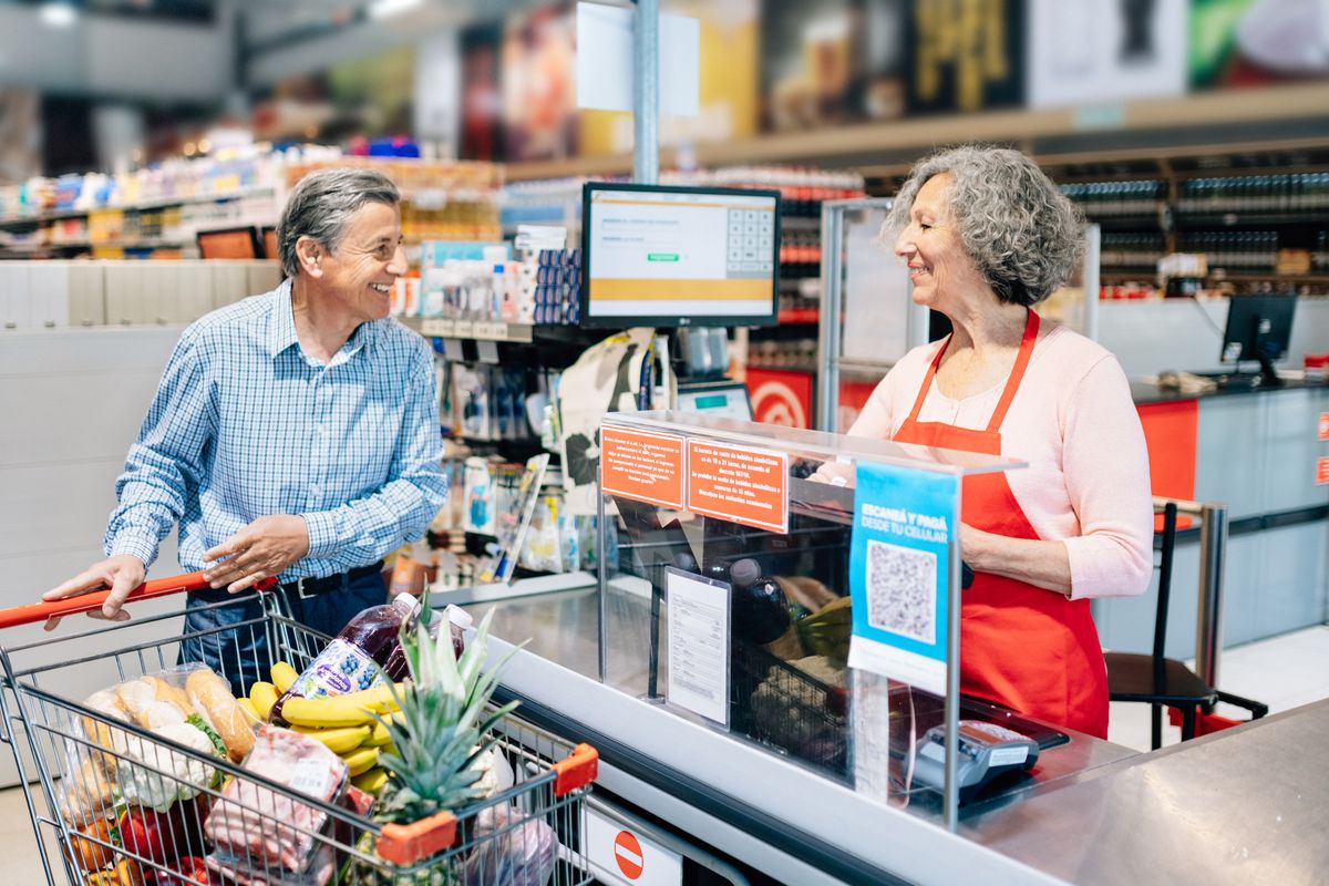 Senior man paying at supermarket cashier Senior woman working as supermarket cashier