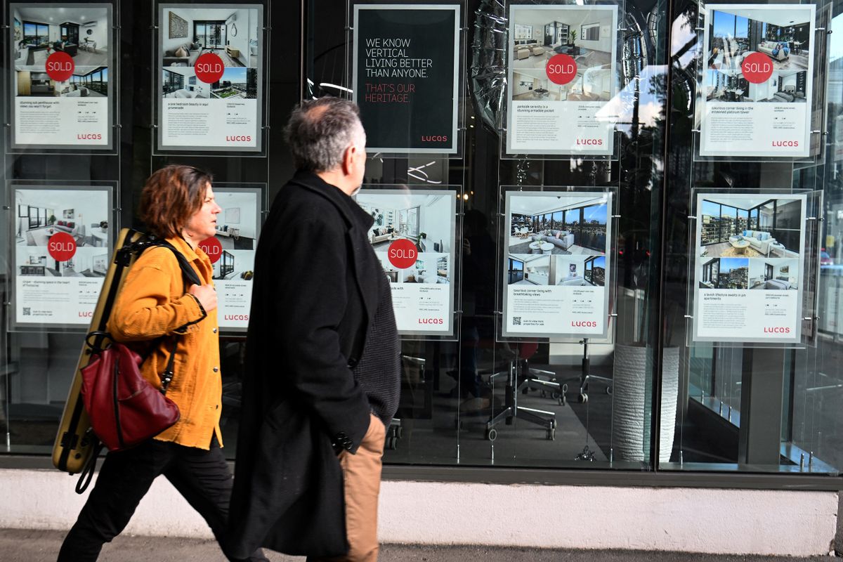 People pass a real estate agency in Melbourne on July 5, 2022, with Australia's Reserve Bank expected to announce a 0.5 percentage point increase in interest rates. 