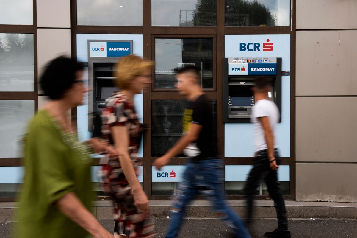 Pedestrians walk past an ATM of the Banca Comerciala Romana in Bucharest, Romania on July 25, 2018. 