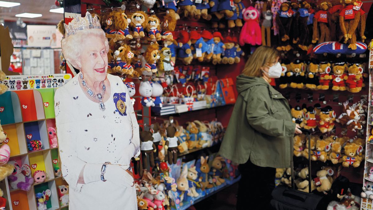 A shopper browses souvenirs near to a life-sized cutout of Her Majesty, on display inside the Cool Britannia souvenir shop close to Buckingham Palace in central London, on January 28, 2022. - Pomp, pageantry and puddings will form the centrepiece of celebrations to mark Queen Elizabeth II's 70 years on the throne. The 95-year-old monarch's Platinum Jubilee begins on February 6 -- the date in 1952 when she became queen after the death of her father, King George VI. Britain's longest-serving monarch will be the only queen or king in the country's long history to have ruled for 70 years. (Photo by Tolga Akmen / AFP) BRITAIN-ROYALS-QUEEN-JUBILEE