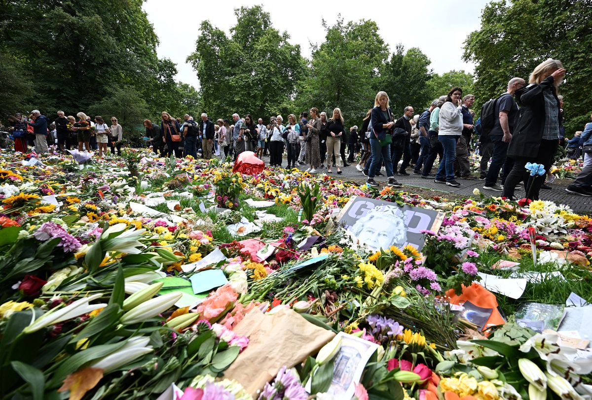 Members of the public look at flowers and tributes left in Green Park in London on September 15, 2022, following the death of Queen Elizabeth II on September 8. - Queen Elizabeth II will lie in state until 0530 GMT on September 19, a few hours before her funeral, with huge queues expected to file past her coffin to pay their respects. (Photo by Paul ELLIS / AFP) BRITAIN-ROYALS-QUEEN-DEATH
