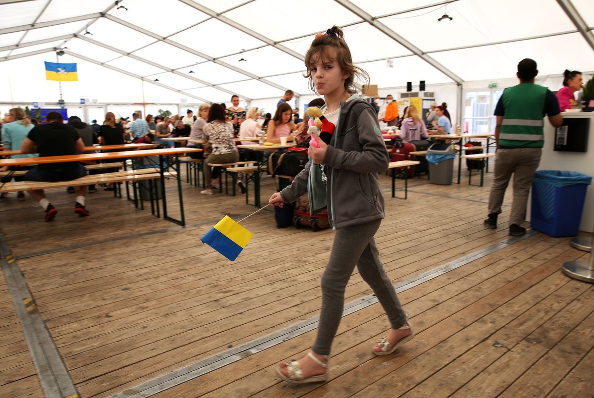 As Ukraine War Reaches 6 Months, New Refugees Arrive While Others Return Home, BERLIN, GERMANY - AUGUST 23: A child refugee from Ukraine holds a Ukrainian flag as she walks through a temporary welcome center tent outside the main train station (Hauptbahnhof) on August 23, 2022 in Berlin, Germany. The following day, August 24, is the 31st anniversary of when Ukraine's parliament vowed to separate from the Soviet Union in 1991 but this year will also mark six months since the country's war with Russia began. Ahead of the holiday, the Ukrainian government is warning civilians against gathering in major cities. Over seven million refugees have left Ukraine since the start of Russia's invasion in the largest mass population displacement in Europe since World War II, with an estimated 900,000 of them seeking permanent or temporary residence in Germany. (Photo by Adam Berry/Getty Images) (Photo by Adam Berry/Getty Images)