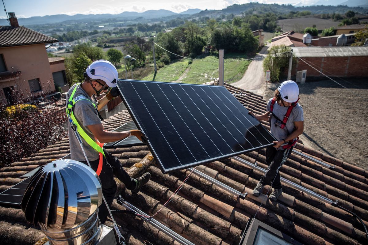 Engineers from Sud Energies Renovables SL place a solar panel onto the roof of a residential property during installation in Barcelona, Spain, on Wednesday, Sept. 7, 2022. Spain and other Mediterranean countries generated record amounts of power from wind and solar farms, underscoring the potential for renewables to replace expensive fossil fuels. 