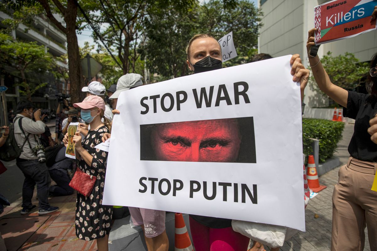 Thais Rally Against War In Ukraine, BANGKOK, THAILAND - FEBRUARY 25: A Ukrainian protester holds up a poster of Russian President Vladimir Putin that reads "Stop war, stop Putin" during a rally outside the Russian Embassy on February 25, 2022 in Bangkok, Thailand. Protests have erupted around the world in support of Ukraine after Russian forces invaded the country yesterday. (Photo by Lauren DeCicca/Getty Images)