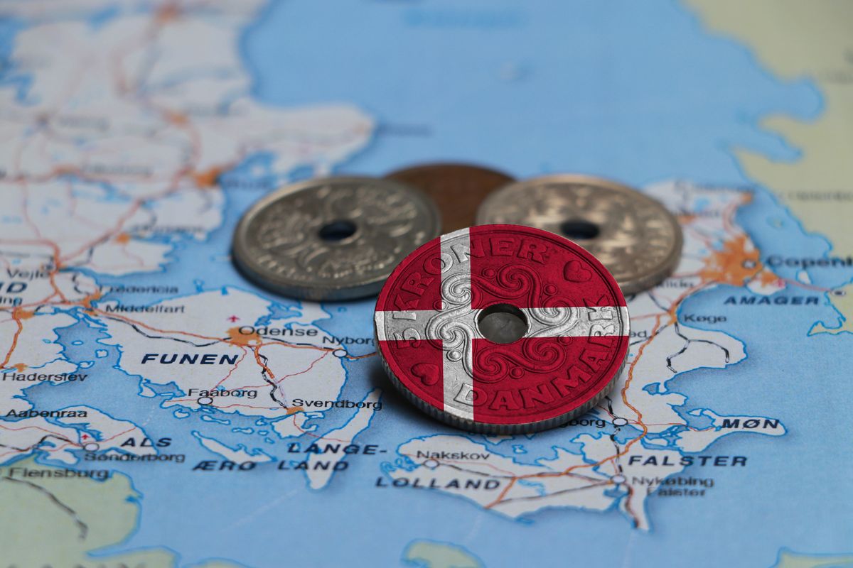 Denmark,Flag,On,The,Coin,With,Heap,Of,Danish,Kroner, Denmark flag on the coin with heap of Danish Kroner money on the map. Concept of finance or currency or travel. Denmark flag on the coin with heap of Danish Kroner money on the map. Concept of finance or currency or travel.