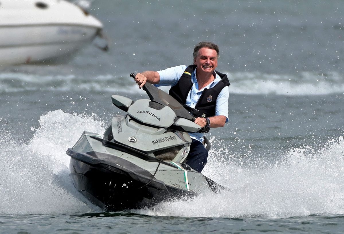 (FILES) In this file photo taken on May 15, 2022, Brazilian President Jair Bolsonaro rides a jet ski as he joins supporters taking part in a boat ride on Paranoa Lake in Brasilia. - The outgoing Brazilian president Jair Bolsonaro, beaten in all the polls by his sworn enemy Lula, says he is sure of his victory in the first round of the October 2, 2022 election after four years of a mandate marked by crises. 