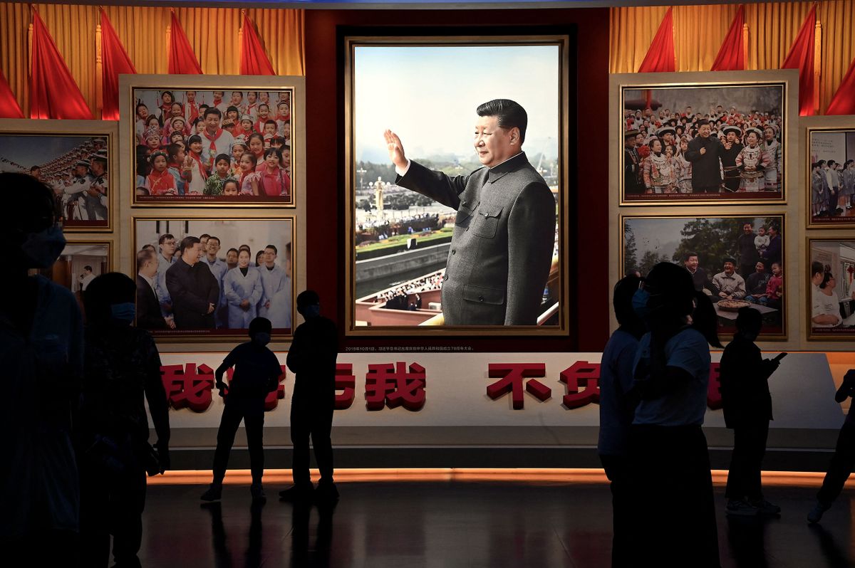 People stand in front of images of Chinese President Xi Jinping at the Museum of the Communist Party of China in Beijing on September 4, 2022. 
