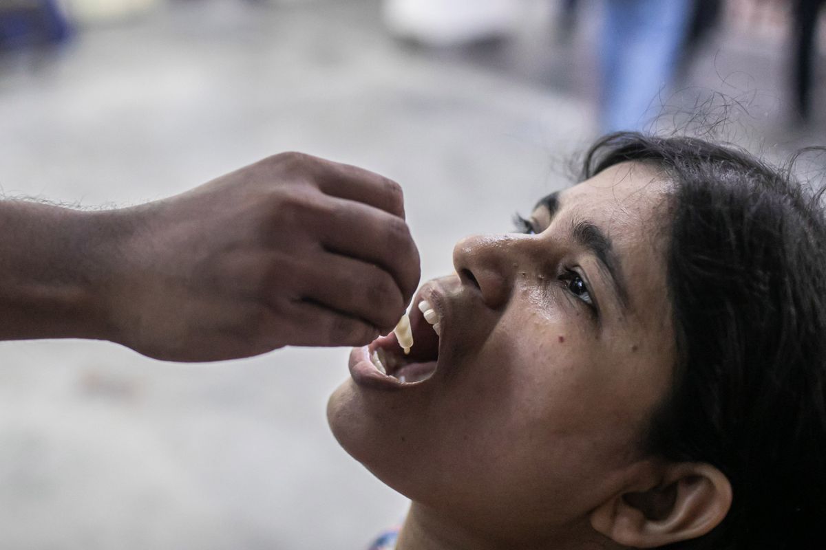 DHAKA, BANGLADESH - 2022/06/28: A student receives an oral cholera vaccine from a health worker during the vaccination campaign. The government is set to start administering an oral vaccination campaign to reduce the incidences of diarrhea and cholera in the country. Under the campaign, the health directorate will vaccinate around 2.3 million people with the first dose of vaccines in five diarrhea-prone areas of the capital. The World Health Organization is providing Cholera vaccines and financial support for the implementation of the immunization campaign. (Photo by /SOPA Images/LightRocket via Getty Images)