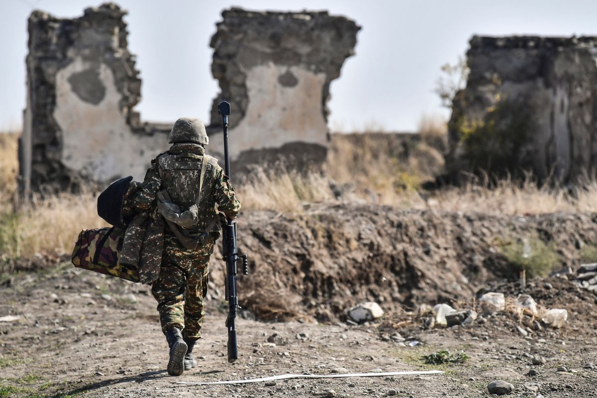An Armenian soldier carries his machine gun at the front line at troops hold positions on October 18, 2020, during the ongoing fighting between Armenia and Azerbaijan over the disputed region. (Photo by ARIS MESSINIS / AFP)