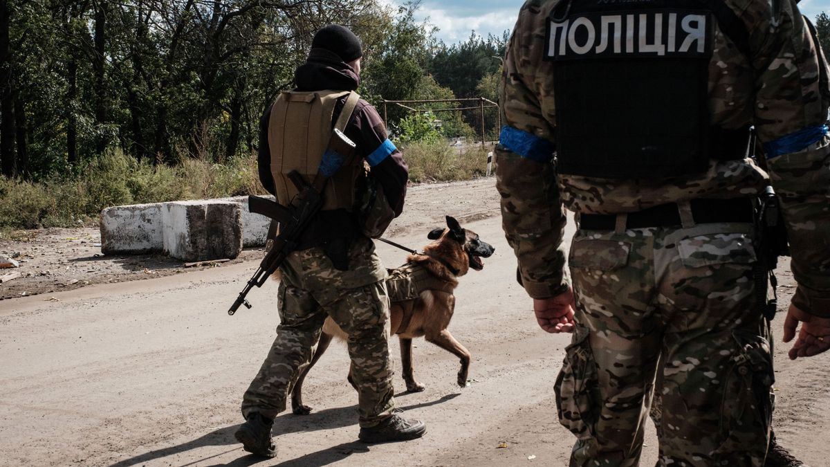 Andriy Symchuk, National Police officer of Liviv region, stands with 'Bars' his sniffer dog at a checkpoint in Izyum, Kharkiv region, on September 25, 2022, amid the Russian invasion of Ukraine. (Photo by Yasuyoshi CHIBA / AFP)