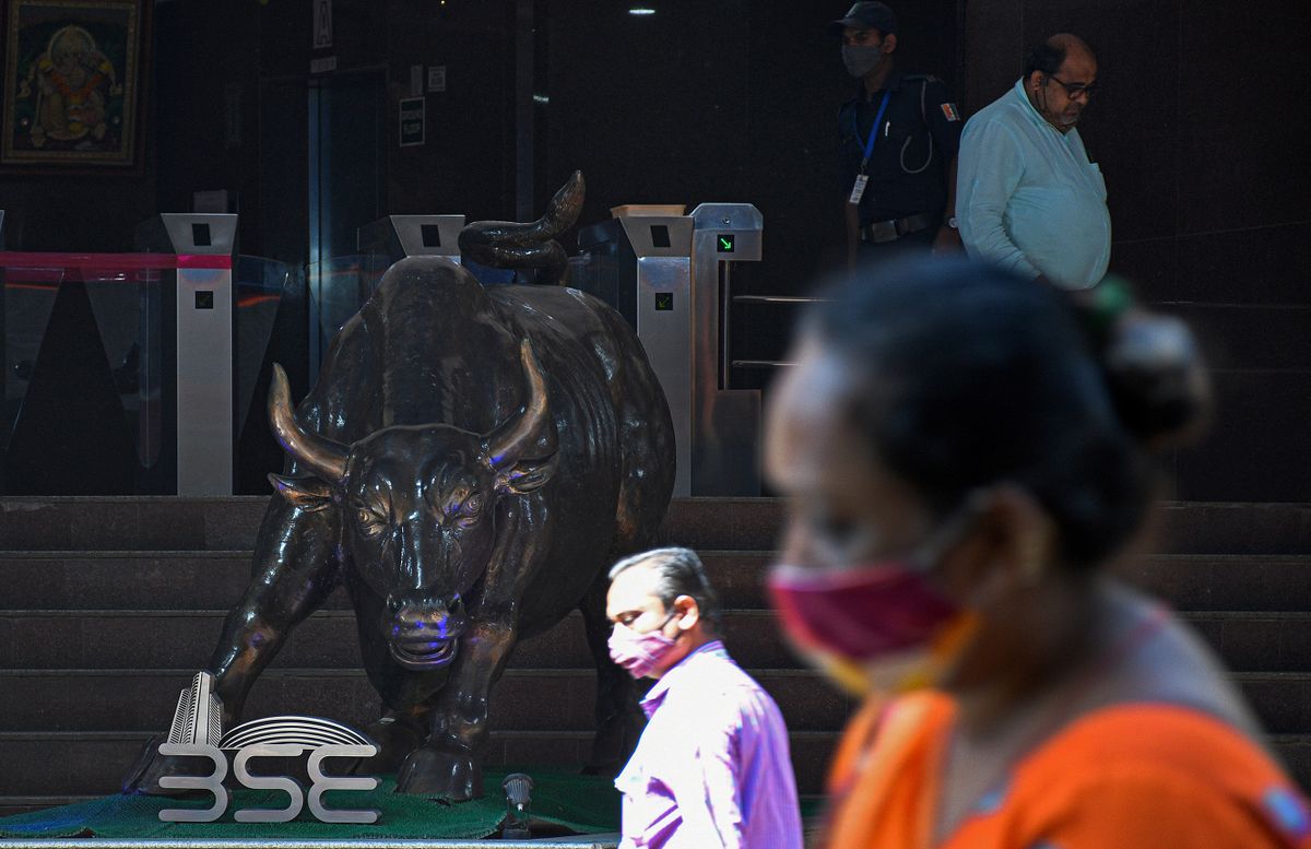 MUMBAI, MAHARASHTRA, INDIA - 2022/02/01: People wearing protective face masks walk past a statue of bull near Bombay Stock Exchange (BSE) building in Mumbai.Stock prices rise if the Union Budget is perceived positively and the prices of stocks drop if the stock exchange doesn't find the budget in its favour. 