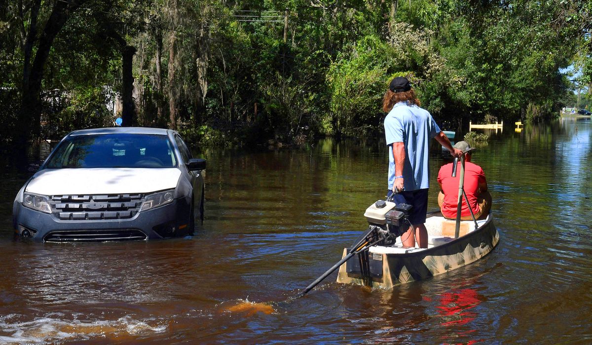 Hurricane Ian Aftermath in Orlando, ORLANDO, FLORIDA, UNITED STATES - OCTOBER 1: Two men motor a boat past a stranded car to pick up items from a home that was flooded by rain from Hurricane Ian on October 1, 2022 in Orlando, Florida. The storm caused widespread flooding in several areas of Orlando after making landfall in the Fort Myers area as a Category 4 hurricane. Paul Hennessy / Anadolu Agency (Photo by Paul Hennessy / ANADOLU AGENCY / Anadolu Agency via AFP)