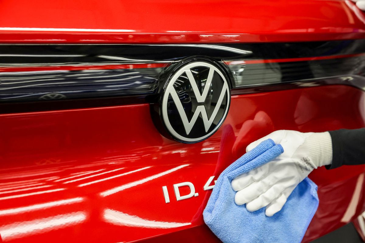 Production of e-vehicles at VW in Zwickau 26 April 2022, Saxony, Zwickau: An employee wipes over the VW logo on an ID.4 in the light tunnel at Volkswagen's plant in Zwickau. In addition to VW vehicles, vehicles from the Group's Audi and Seat brands also come off the production line at the plant. The vehicles are based on the Modular Electric Toolkit. Volkswagen has converted the site, which employs around 9,000 people, into a purely electric vehicle factory at a cost of 1.2 billion euros. Photo: Jan Woitas/dpa (Photo by JAN WOITAS / DPA / dpa Picture-Alliance via AFP)