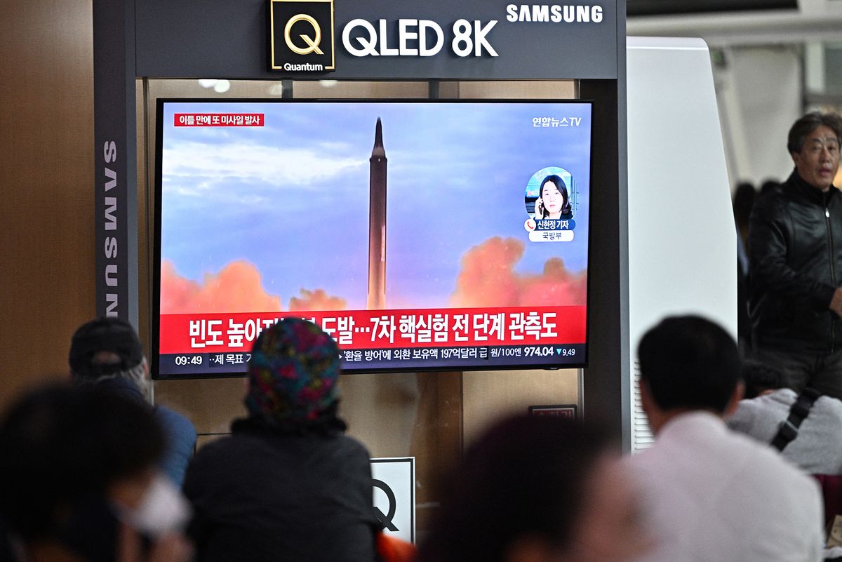 People sit near a television showing a news broadcast with file footage of a North Korean missile test, at a railway station in Seoul on October 6, 2022. - North Korea fired two ballistic missiles on October 6 as it justified its recent blitz of sanctions-busting tests as necessary countermeasures against joint military drills by the United States and South Korea.