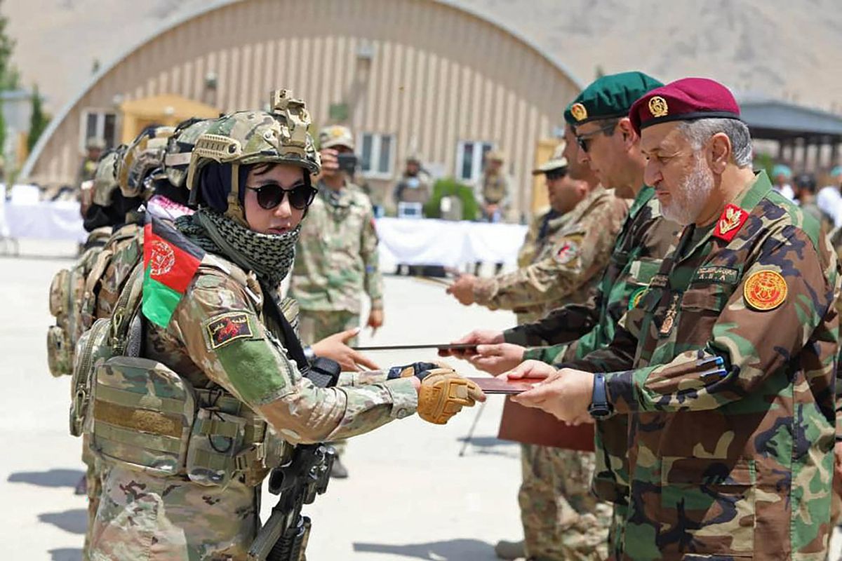This handout photograph taken on July 17, 2021 and released by Afghanistan's Ministry of Defence Office shows Afghan Defence Minister General Bismillah Khan Mohammadi (R) attending the graduation ceremony of Afghan Army Commandos (L) at the Kabul Military Training Centre (KMTC) in Kabul. 