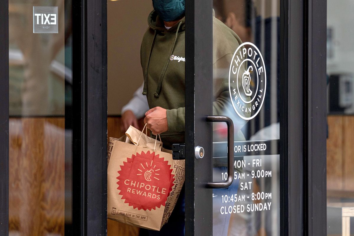 A Chipotle Restaurant Ahead Of Earnings Figures, A person holding a Chipotle bag exits a restaurant in San Francisco, California, U.S., on Monday, April 19, 2021. Chipotle Mexican Grill Inc. is scheduled to release earnings figures on April 21. Photographer: David Paul Morris/Bloomberg via Getty Images
