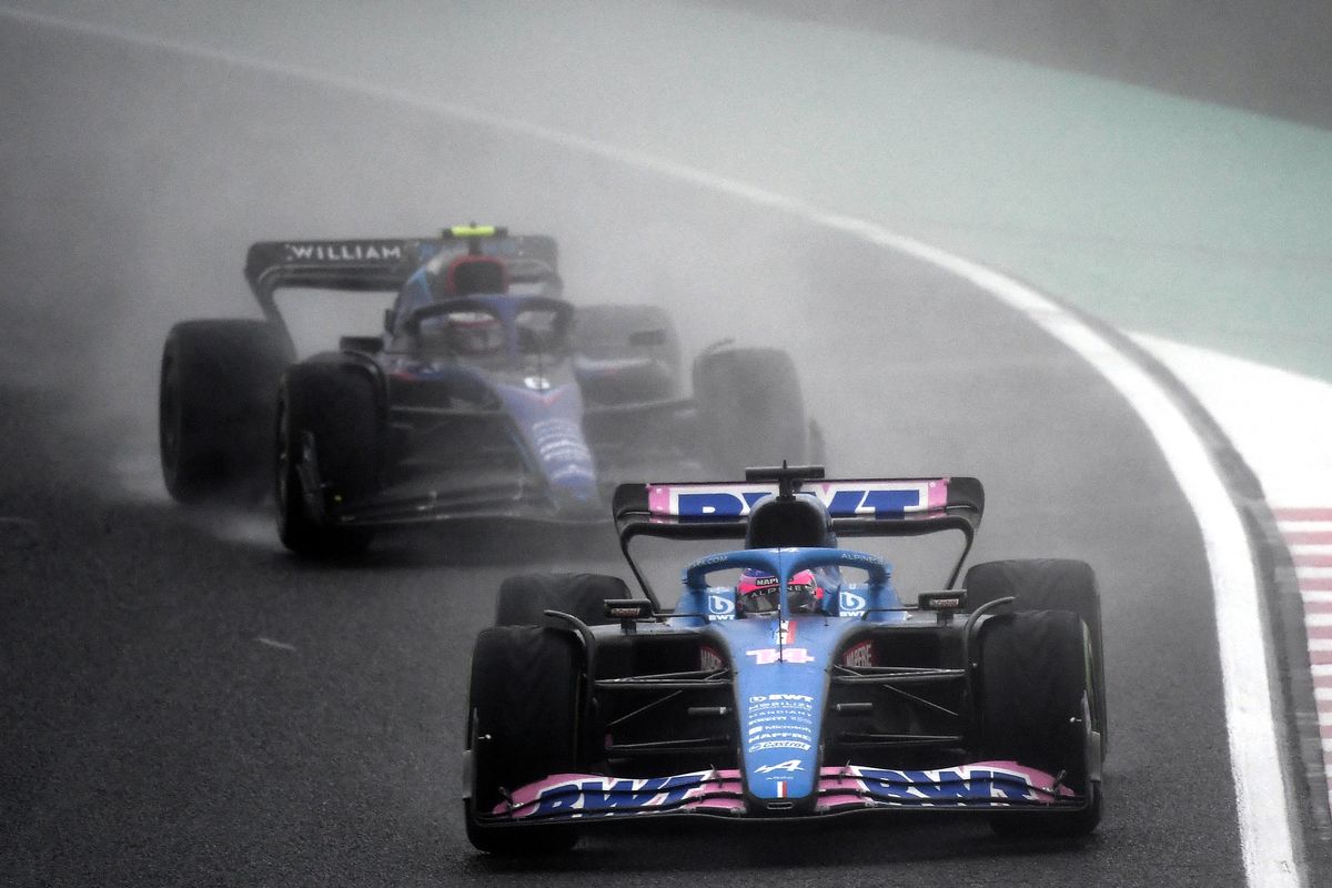 Alpine's Spanish driver Fernando Alonso (C) drives in front of Williams' Canadian driver Nicholas Latifi during the Formula One Japanese Grand Prix at Suzuka, Mie prefecture on October 9, 2022. (Photo by Toshifumi KITAMURA / AFP)