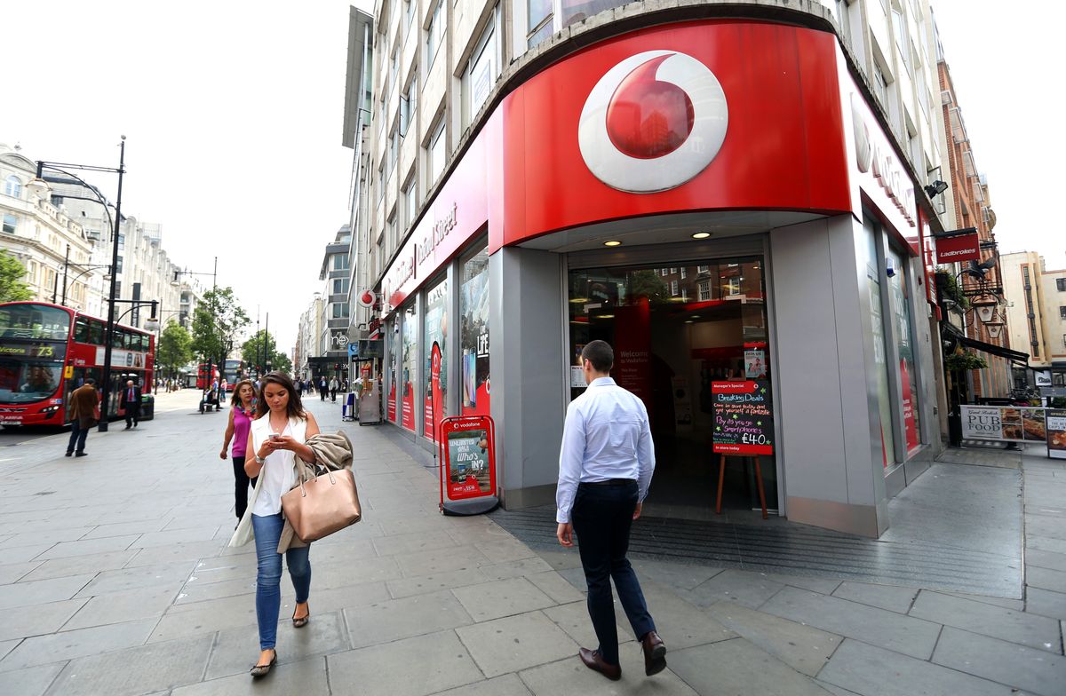 Vodafone Group Plc Stores As Asset Swap Talks With Liberty Global Plc Begin, Pedestrians walk past a Vodafone store, operated by Vodafone Group Plc, in London, U.K., on Friday, June 5, 2015. Vodafone Group Plc said its in talks to exchange assets with billionaire John Malones Liberty Global Plc in a deal between two of Europes biggest wireless and cable providers. Photographer: Chris Ratcliffe/Bloomberg via Getty Images