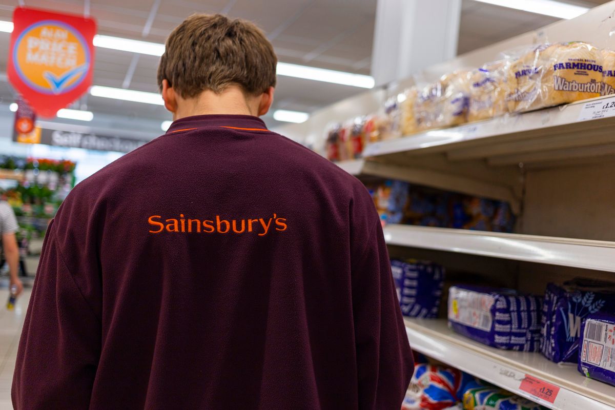 UK Sainsbury's Supermarket Employee, A uniformed staff member of supermarket chain Sainsbury's goes about their work in the bread aisle as the company's board of shareholders will vote this week on a commitment to pay both its staff and its contracted workers the National Living Wage on 3rd July, 2022 in Leeds, United Kingdom. Share Action, an investment campaigning group, has criticised the supermarket, the second-largest in the country, for failing to pay all of its subcontracted staff the National Living Wage. (photo by Daniel Harvey Gonzalez/In Pictures via Getty Images)
