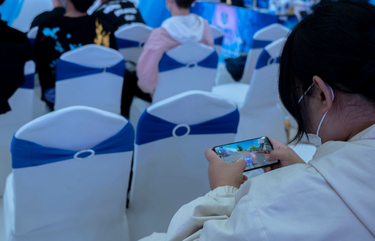 TIANJIN, CHINA - 2021/11/06: A girl is playing the video game of League of Legends on her mobile phone.  League of Legends (LoL),  is a multiplayer online video game developed and published by Riot Games, very popular among Chinese young people.