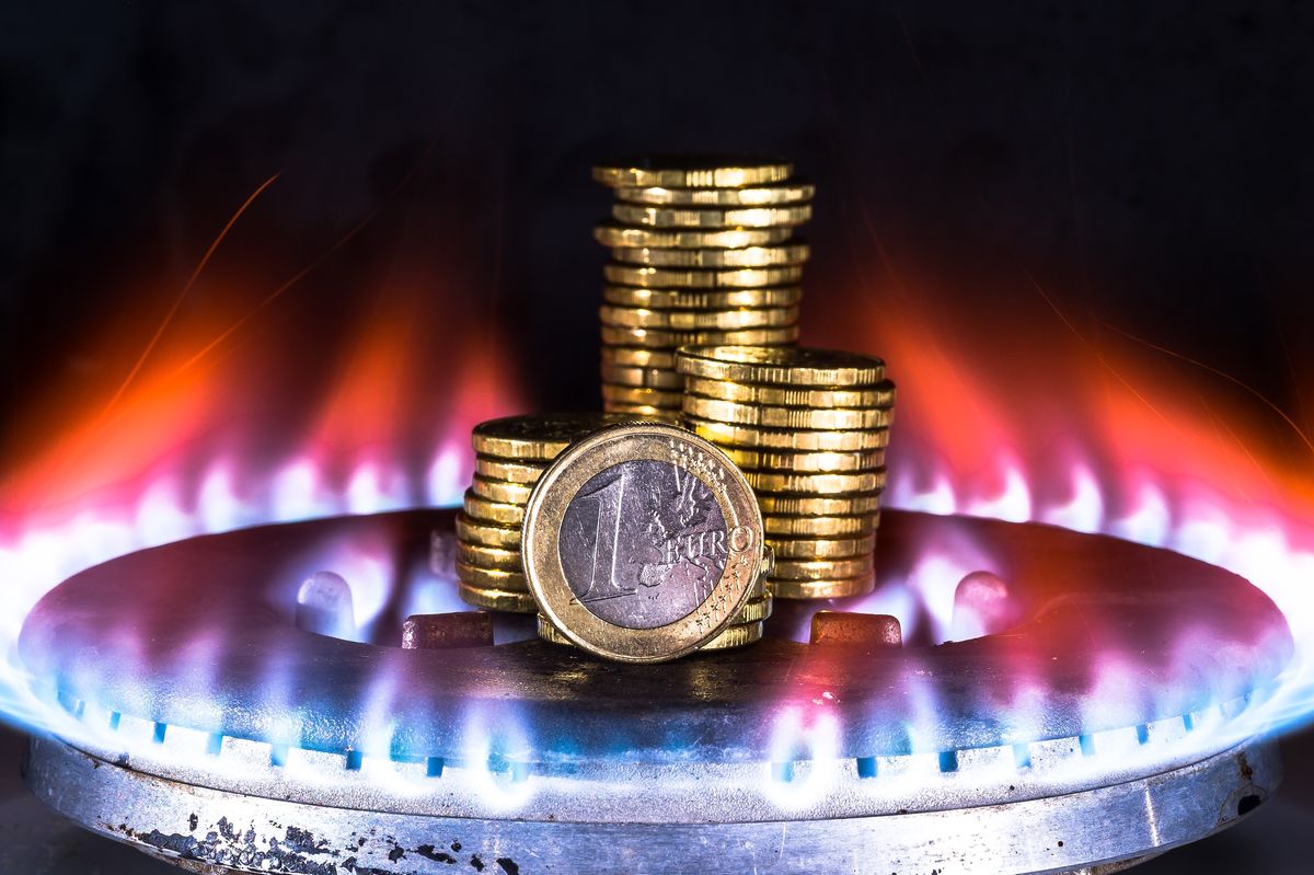 A euro coin closeup along with a row of yellow coins on a gas burner against a blue flame of natural gas on a dark background. The concept of increasing the cost of natural gas. Background A euro coin closeup along with a row of yellow coins on a gas burner against a blue flame of natural gas on a dark background. The concept of increasing the cost of natural gas. Background.európa, gáz, ár, sapka, gázár, unio,