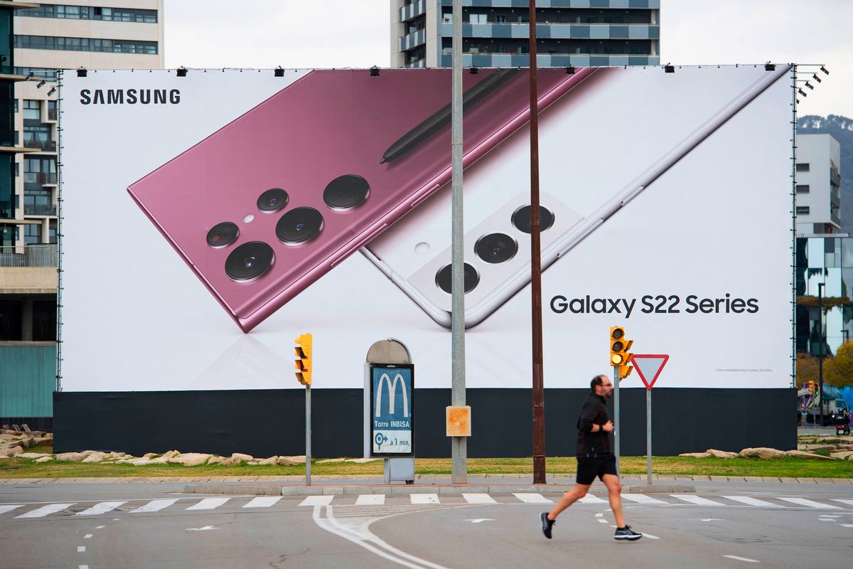 A man runs past a Samsung banner at the entrance of the Fira centre in Barcelona on February 25, 2022, two days ahead of the MWC (Mobile World Congress). - The world's biggest mobile fair is held from February 28 to March 3, 2022. (Photo by Josep LAGO / AFP)