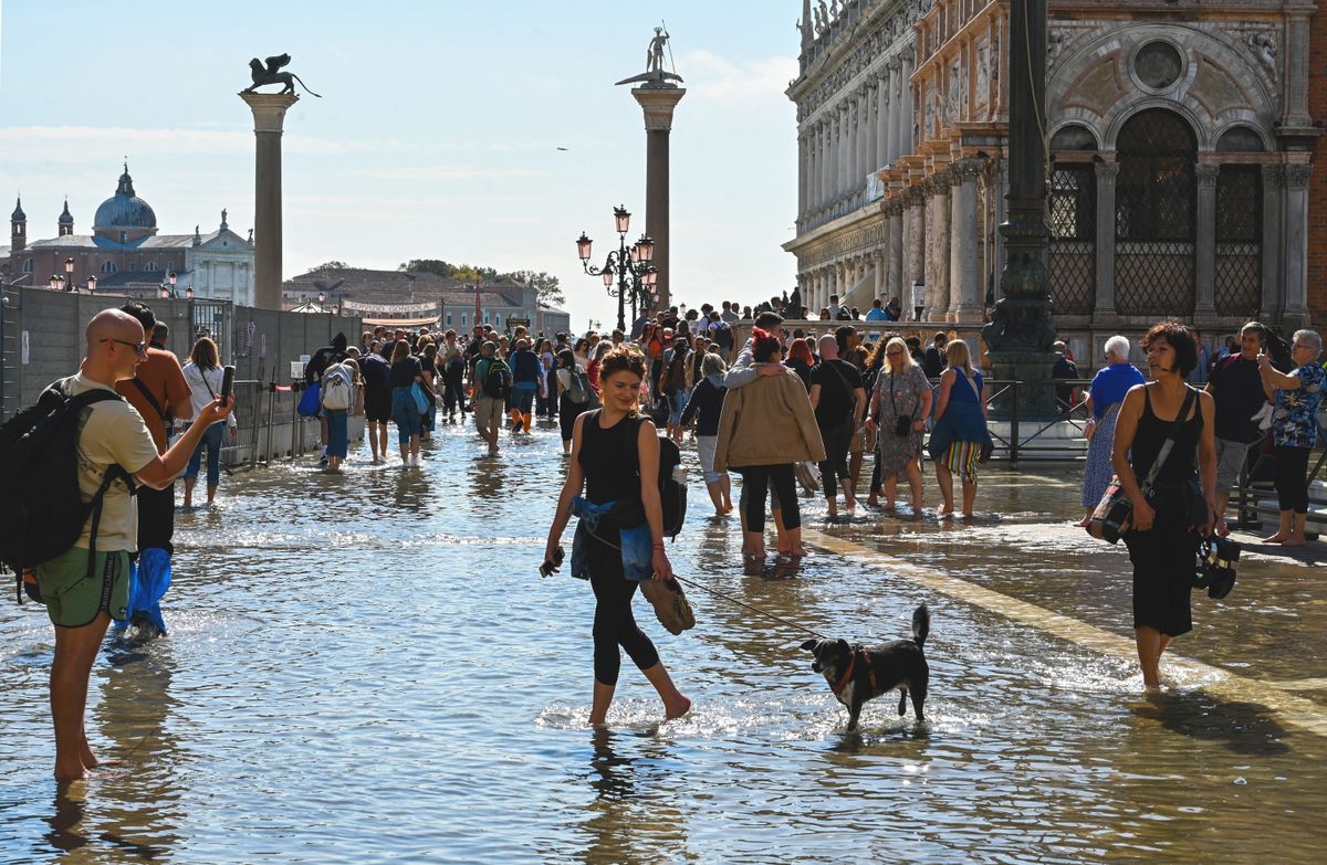 Tourists take photos on a flooded St. Mark's square by St. Mark's basilica in Venice on September 27, 2022, following an "Alta Acqua" high tide event, too low to operate the MOSE Experimental Electromechanical Module that protects the city of Venice from floods, but high enough to potentially threaten St. Mark's Basilica. (Photo by ANDREA PATTARO / AFP)