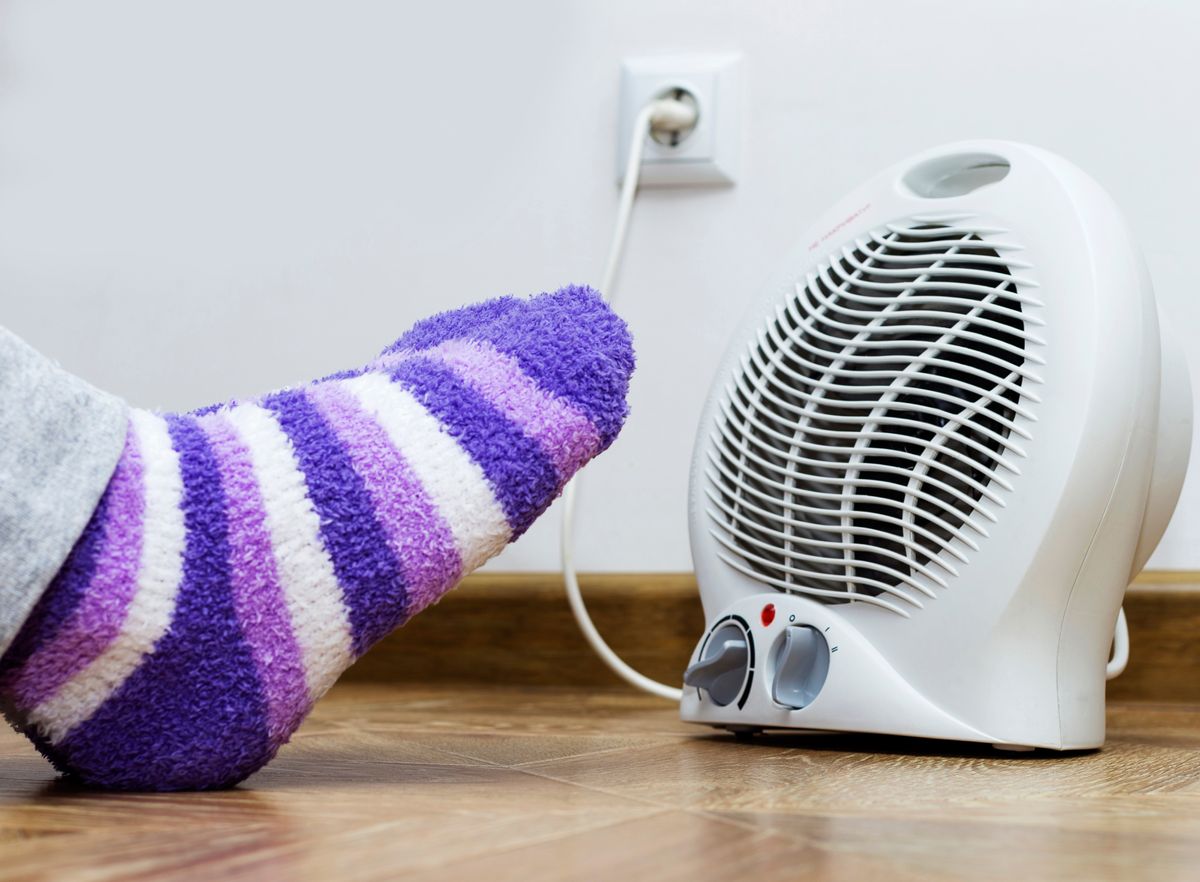 A,Woman,Warms,Her,Feet,In,Front,Of,Electric,Heater. A woman warms her feet in front of electric heater. Warm terry socks. Cropped image. elektromos, konvektor, emag, fűtés, fűtőberendezés, hősugárzó,