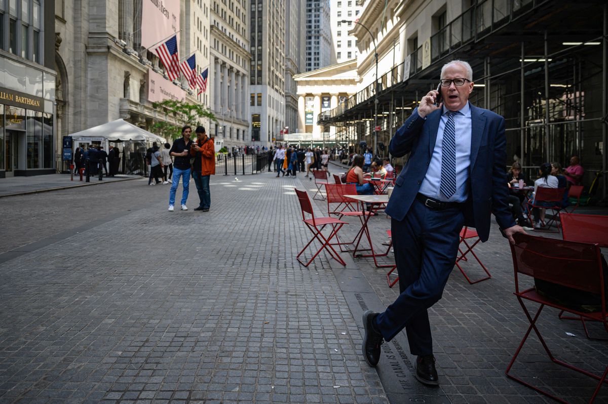 A man speaks on a phone outside the Stock Exchange in New York on June 14, 2022. - Stock markets diverged on Tuesday as investors fret over the possibility that the US Federal Reserve will move aggressively to combat inflation. (Photo by Ed JONES / AFP) amerika, tőzsde, utcakép, üzletember, öltöny