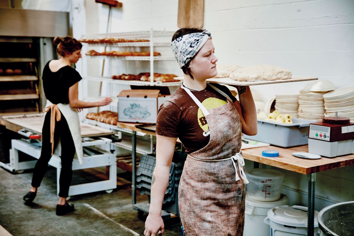 Female baker carrying dough on pastry board through bakery, Female baker carrying dough on pastry board through bakery, ksh, kisvállalkozás, pék, pékség, 