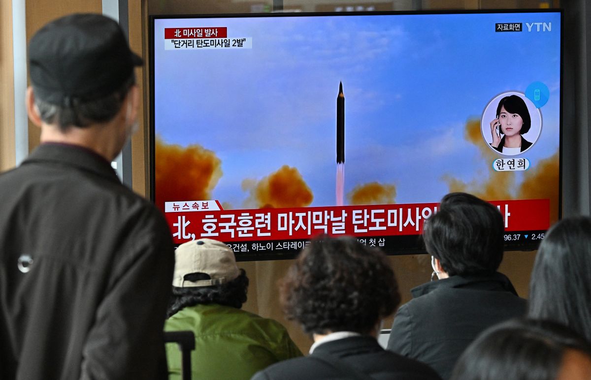 People watch a television screen showing a news broadcast with file footage of a North Korean missile test, at a railway station in Seoul on October 28, 2022