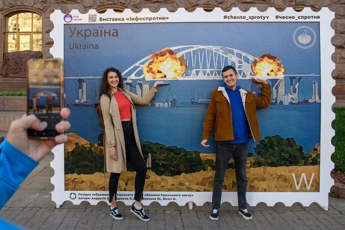 People Pose For Photos In Front Of The Large Poster Depicting The Crimean Kerch Bridge On Fire