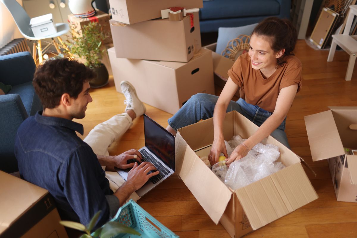 A young couple packing/unwrapping moving boxes, A happy young couple moving into a new apartment, költözés, 