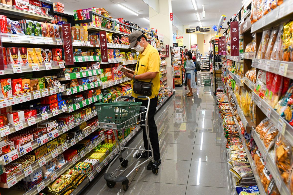 Inside Summit Supermarket As Stay-at-home Olympics Boost Its Food and Alcohol Sales A customer picks up a snack at a Summit supermarket store in Tokyo, Japan, on Tuesday, July 27, 2021. Tokyo's delayed Olympics is flipping conventional wisdom on its head, with Japan's stay-at-home stocks expected to emerge as winners rather than once-favored advertisers, real-estate firms and travel operators. Photographer: Noriko Hayashi/Bloomberg via Getty Images