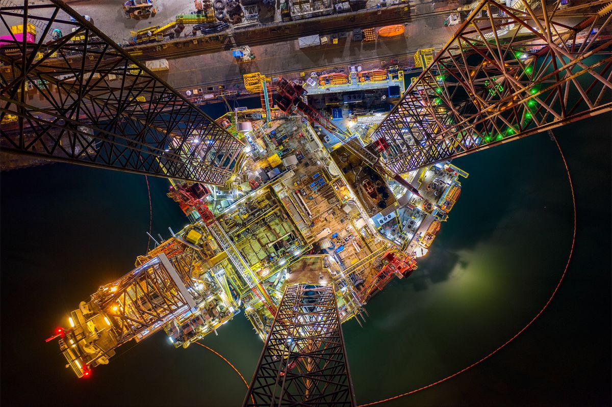 Oil and gas jack-up rig at the yard for maintenance with many vessels in the nighttime, the petroleum rig is applied for producing oil and gas in offshore in the petroleum  industry.Oil and gas jack-up rig at the yard for maintenance with many vessels in the nighttime, the petroleum rig is applied for producing oil and gas in offshore in the petroleum industry. nemzetküzi, olajhelyzet, olaj, fúrótorony,