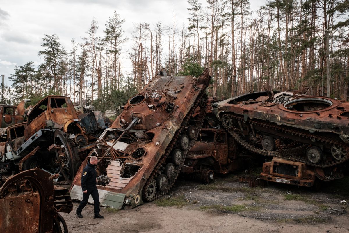 A police officer walks past destroyed Russian armoured vehicles were gathered at a collection point in an animal feed plant in the recently retaken town of Lyman in Donetsk region, on October 5, 2022, amid the Russian invasion of Ukraine.
