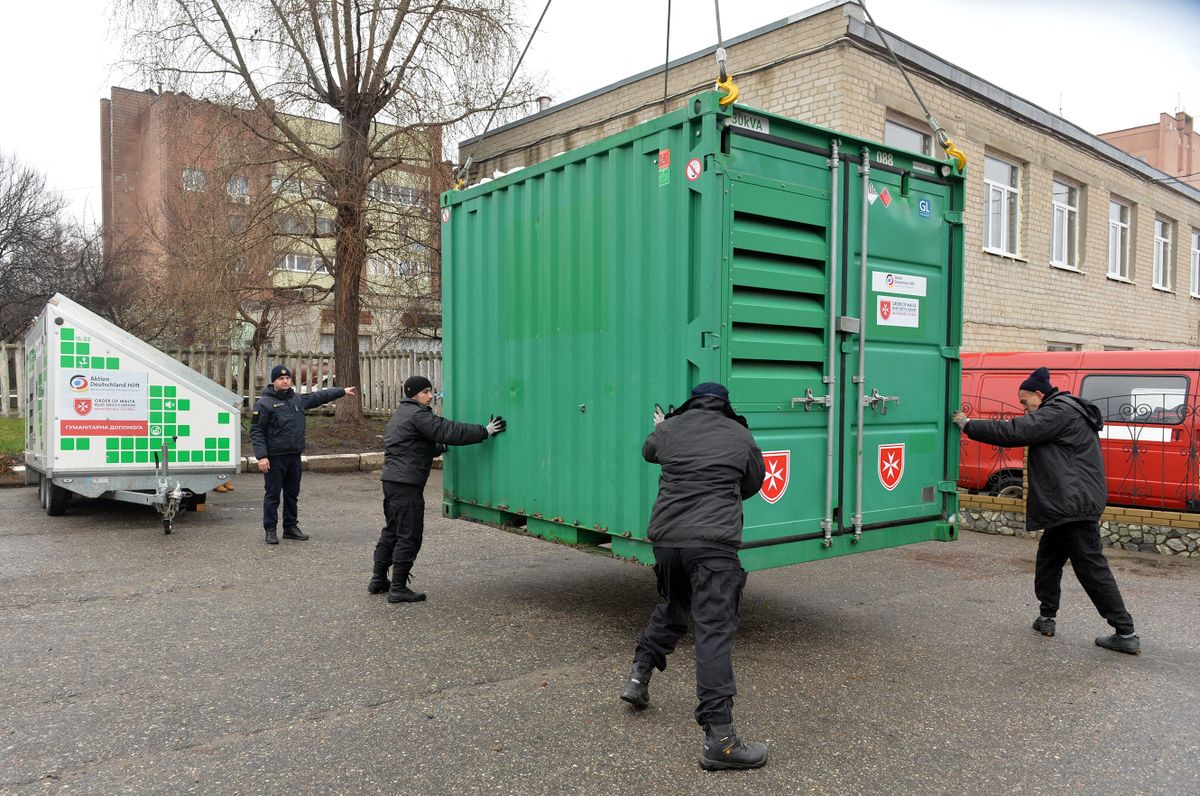 Employees of the State Emergency Service of Ukraine unload mobile power generating station as part of international humanitarian aid in the city of Kharkiv on November 21, 2022, amid the Russian military invasion of Ukraine. - The station will be used to provide electricity to rescuers and the local population in areas where there is no power supply due to the destruction of energy infrastructure facilities by the Russian army. (Photo by SERGEY BOBOK / AFP)