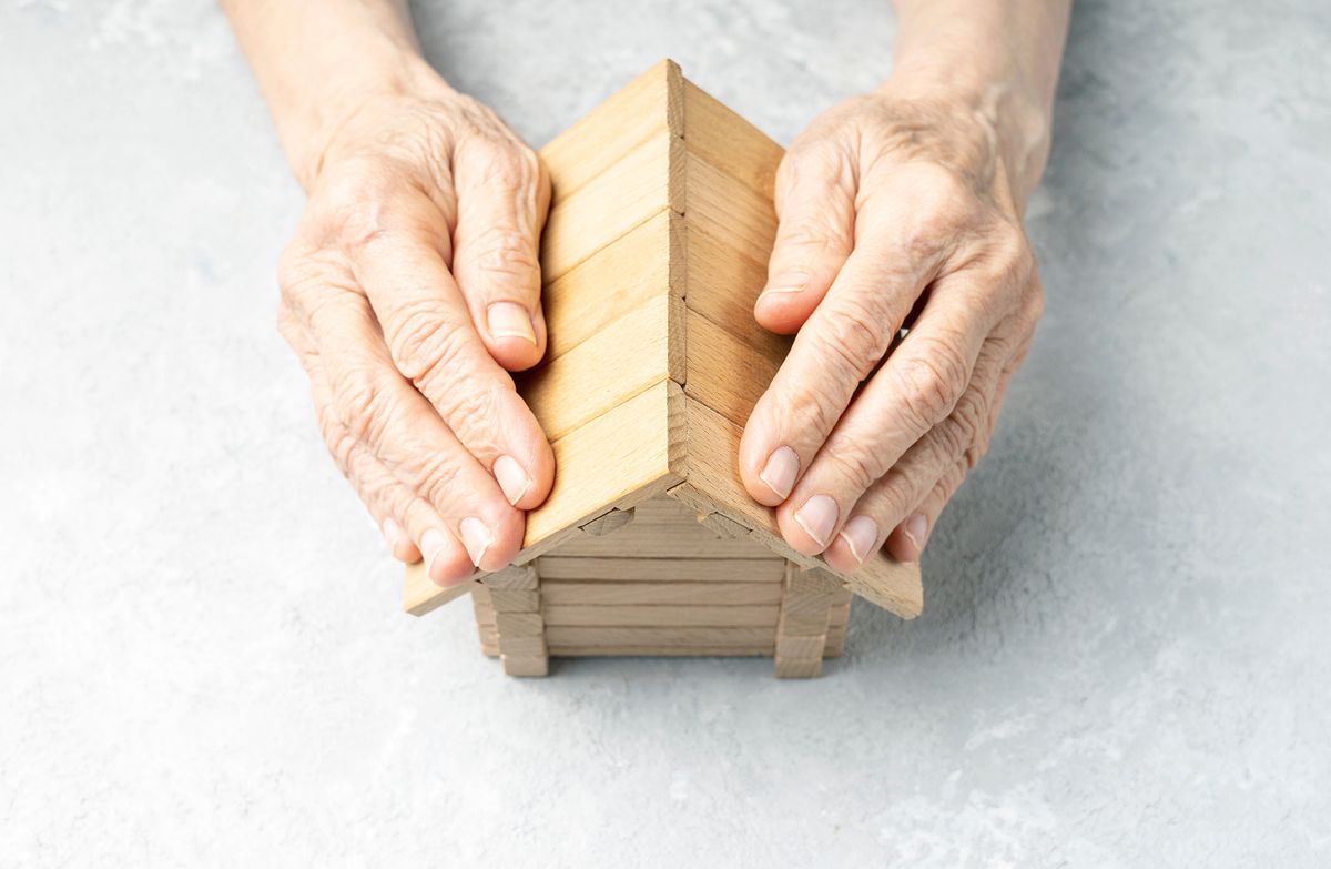 Wrinkled,Hands,Of,An,Elderly,Woman,Protects,The,House.,Taking