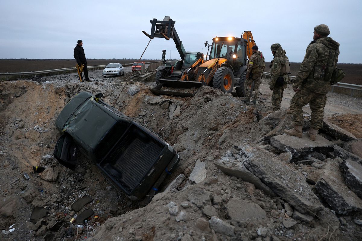 Ukrainian soldiers pull a car out of a crater on the road in Kherson region on November 13, 2022, amid Russia's invasion of Ukraine. - On November 11, 2022, Russia said it had pulled back more than 30,000 troops in the southern region, with Ukrainian President declaring Kherson "ours" as residents reacted with joy and jubilation. 