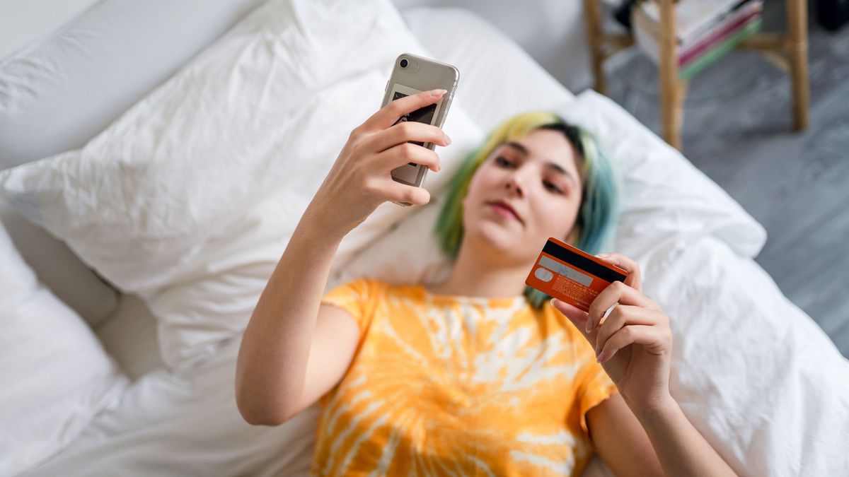 Young woman with colored hair is shopping online with a credit card, Young woman with colored hair is shopping online with a credit card, cashback, cash, visszatérítés, pénz