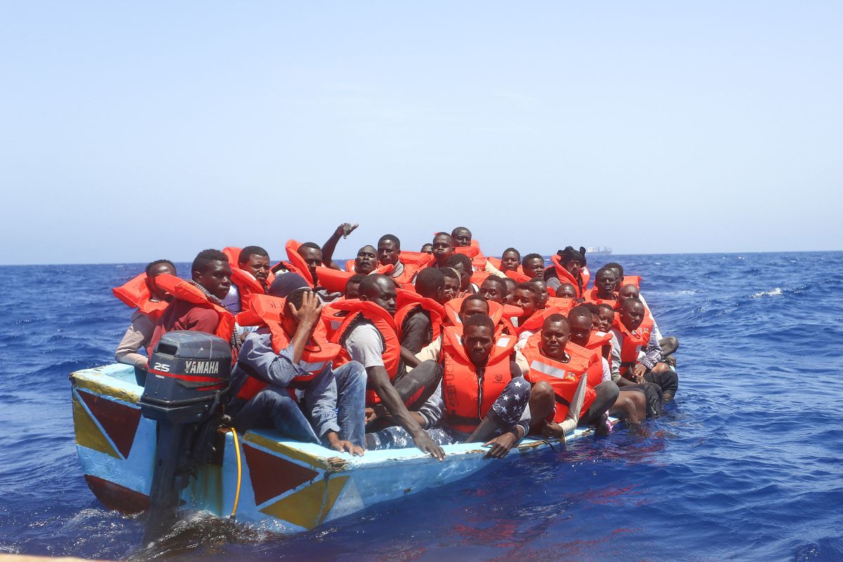 LAMPEDUSA, ITALY - MAY 20: Refugees and migrants are seen floating in an overcrowded wooden boat as they wait to be assisted by search and rescue crew members from NGO Sea-Eye on May 20, 2017 in international waters off the coast of Libya. 
