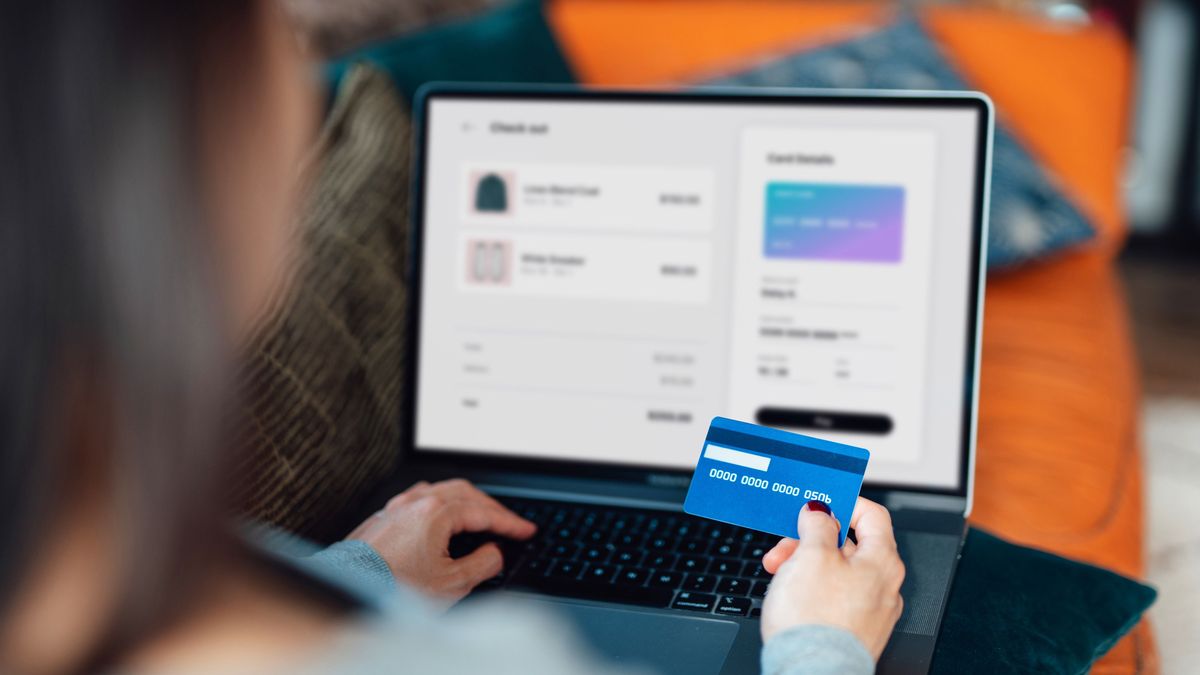 Woman using credit card for online shopping Above the shoulder view of a woman shopping clothes online on laptop, making payment with credit card. Enjoying seasonal sales. Shopaholic concept. Cyber security idea. Close up shot. Laptop screen mockup., online vásárlás, kártya, bankkártya, 